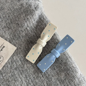 Dettaglio di fermagli per capelli a fiocco con pois in resina bianco crema e blu cielo