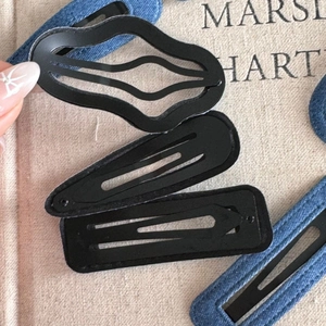 Detail showing assorted metal BB hair clips and denim fabric wrapped clip on book page