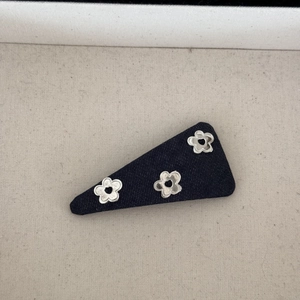 Gros plan sur une barrette triangulaire en jean avec fleurs métalliques argentées
