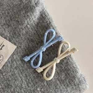 Dettaglio di fermagli per capelli a fiocco a pois in azzurro e crema su maglia morbida