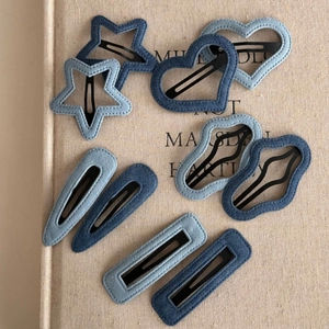 Detailed view of denim fabric hair clips in star, heart, and geometric shapes on a book