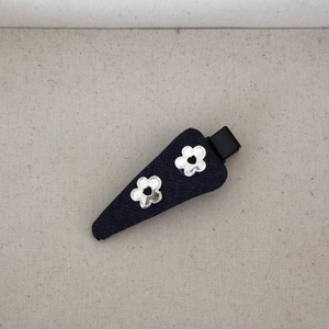 Détail d'une pince à cheveux en denim bleu foncé avec fleurs miroir argentées sur lin