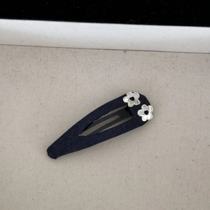 Détail d'une barrette en denim bleu foncé ornée de petites fleurs argentées évidées