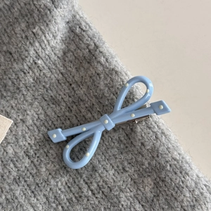 Dettaglio del fermaglio per capelli a fiocco azzurro a pois con clip a becco d'anatra in metallo