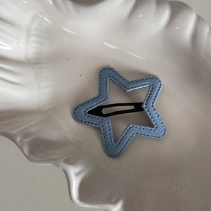 Detail of star-shaped blue denim hair clip with decorative stitching on white plate