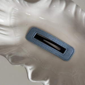Detailed view of light blue denim fabric BB hair clip on a white shell textured tray