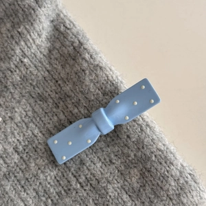 Fermaglio blu a pois per capelli fissato su un maglione grigio lavorato a maglia
