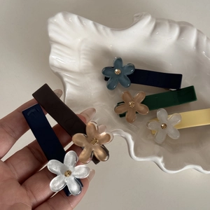 Dettaglio del set di fermagli per capelli floreali in vari colori su un piatto di conchiglia