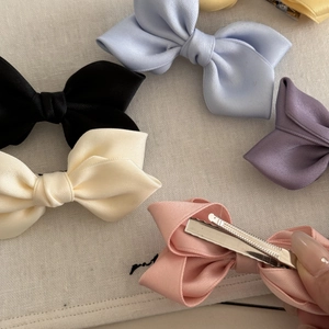 Detail of satin bow hair clips showing metal alligator clip mechanism and color variety