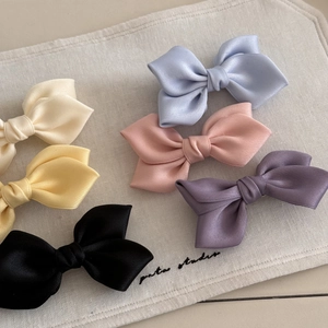 Set of six satin bow hair clips in pastel colors including cream, pink, and blue