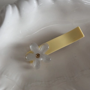 Dettaglio molletta per capelli giallo crema con fiore bianco e strass dorato lucido