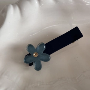 Dettaglio del fermaglio per capelli con fiore blu scuro e perla su vassoio a conchiglia