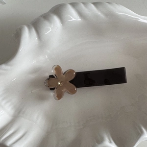 Dettaglio di un fermaglio per capelli marrone con un fiore in resina caffè traslucido