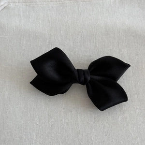Detailed macro shot of the black satin fabric texture on a ribbon hair clip