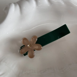Dettaglio del fermaglio per capelli verde scuro con fiore marrone e strass lucido