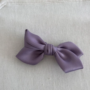Detailed top view of the glossy purple satin fabric bow hair clip with central knot