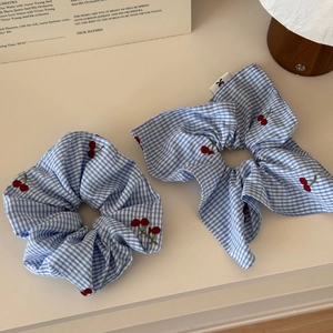 Detail of blue gingham hair scrunchie set featuring red cherry embroidery and bow tie design
