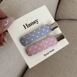 Dettaglio dei fermagli in tessuto a pois rosa e blu su un biglietto fatto a mano