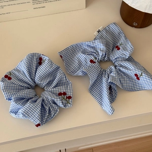 Detailed view of blue gingham hair scrunchies set with embroidered red cherry patterns