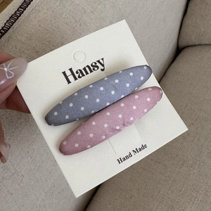Dettaglio di fermagli per capelli a pois rosa e grigi su un cartoncino fatto a mano