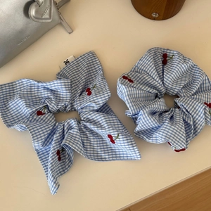 Detail of blue gingham scrunchie set with red cherry embroidery and bow ribbon design