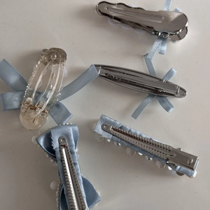 Detail view of the silver metal duckbill clips and blue satin ribbon bow hairpins
