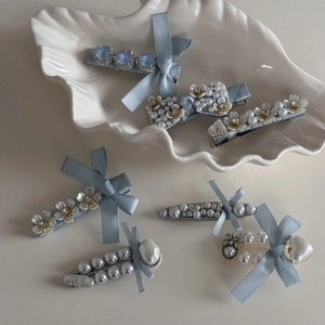 Detail view of light blue satin bow hair clip with pearl accents and crystal floral hairpins
