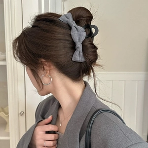 Elegant grey fabric bow hair claw clip for women in a half-up bun hairstyle