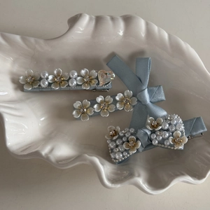 Elegant light blue pearl and rhinestone bow hair clip set displayed on a white shell tray