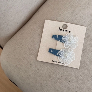 Détail de pinces à cheveux bleues à pois avec fleurs en dentelle blanche et perles