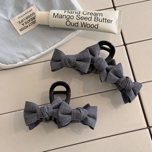 Detailed view of grey fabric bow hair claws with elegant suit-texture material