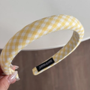 Detail eines gelben Gingham-Stoffstirnbands mit handgefertigtem Etikett und Textur