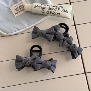 Detailed macro view of the grey fabric bow hair claw clip showing woven textile texture
