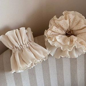 Detailed view of cream-colored pleated organza hair scrunchie with hollow lace edges