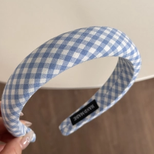 Detailaufnahme des blau-weiß karierten Haarreifs mit handgefertigtem Etikett und Textur
