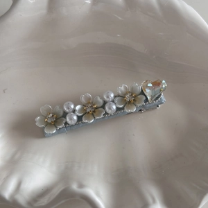 Detail of elegant pearl bow hair clip with rhinestones and floral fabric accents