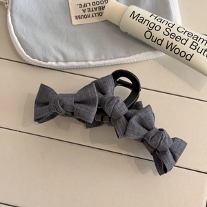 Detail of grey bow hair claw clip with linen texture on a stylish lifestyle background