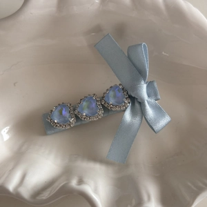 Detail of light blue bow hair clip with heart-shaped crystals and silver rhinestone accents