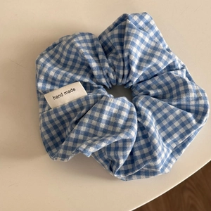 Detailaufnahme von blau-weißem Gingham-Haargummi mit handgefertigtem gewebtem Etikett
