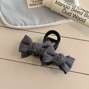 Detail of grey checkered fabric bow hair claw clip with a refined minimalist texture