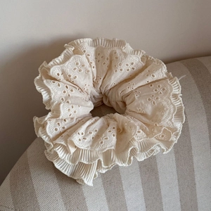Detail of four-layer cream eyelet lace scrunchie showing intricate pleated embroidery texture