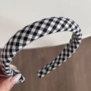 Detailaufnahme eines schwarz-weißen Haarreifens mit Gingham-Muster aus Textilstoff