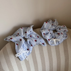 Detail of blue plaid strawberry hair scrunchies with white lace and bow accents