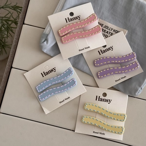 Detailed macro view of wavy macaron hair clips with contrast stitching on display cards