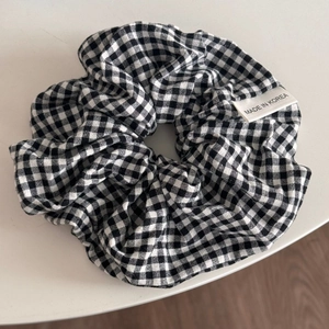 Detail eines schwarz-weißen Gingham-Stoff-Scrunchies mit einem Made in Korea Etikett