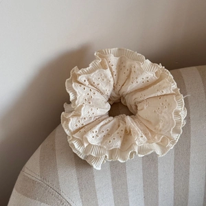 Detail of multi-layered cream eyelet lace scrunchie with fine pleated edges and textures