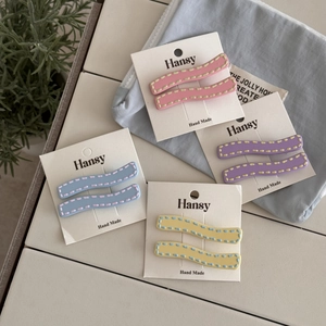 Close-up of pastel wavy hair clips with stitch detail on minimalist display cards