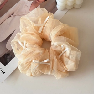 Detail of elegant champagne mesh scrunchie with delicate white bow patterns for women