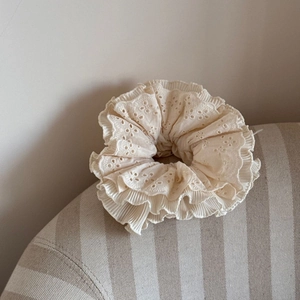 Detailed macro view of cream layered lace scrunchie with hollow embroidery and pleated edges