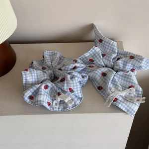 Detail of blue plaid scrunchie with strawberry patterns and white lace trim edge